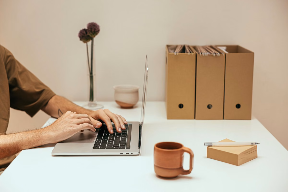 Mains tapant sur un ordinateur portable dans un espace de travail clair