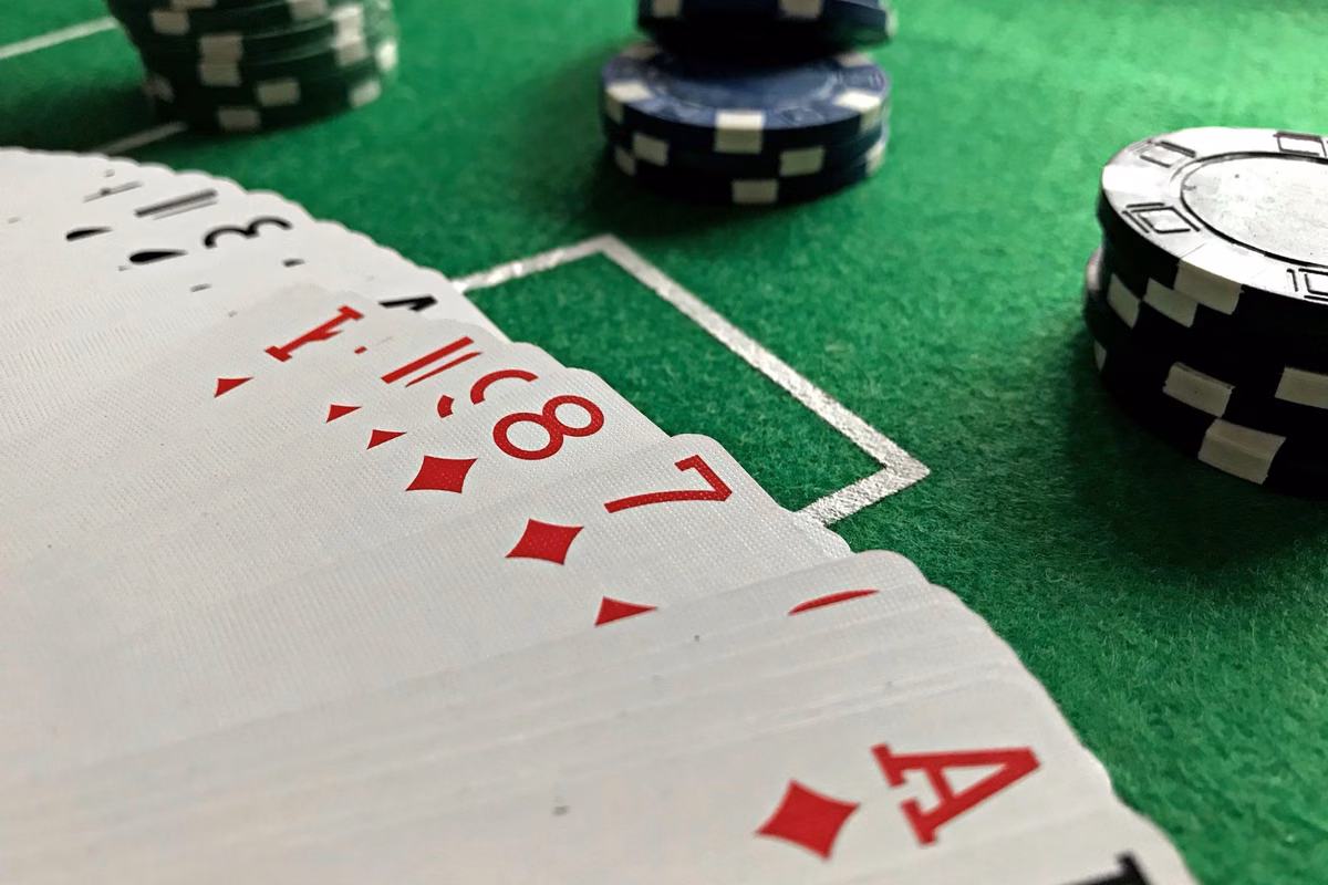 Cartes étalées et jetons de poker sur un tapis vert, en gros plan